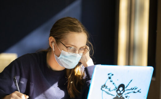 A student studying from a laptop while masked at Hodges Library