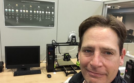 Image of IT technologist Richie Sexton, sitting in front of one of Pendergrass Library's 3D Printers