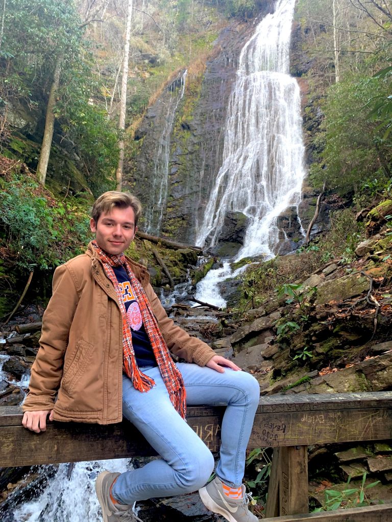 Student worker Evan Bushart posing in front of a waterfall