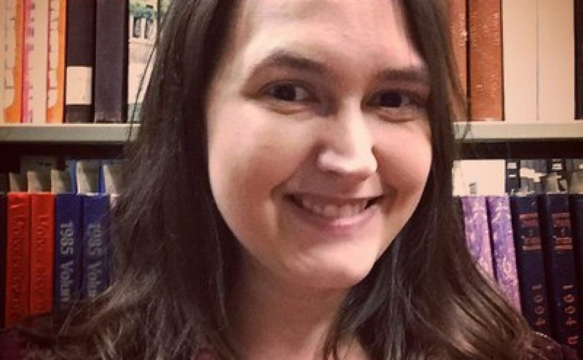 Image of Becky Briggs Becker in front of shelves of books