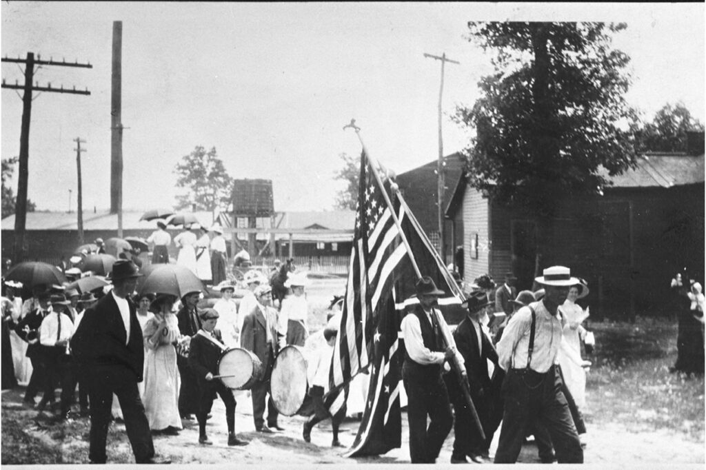 Fourth of July parade, Tracy City, Tenn., 1909. Men are carrying flags and boys are playing drums.